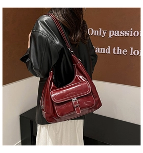Detail of burgundy glossy tote bag featuring white contrast stitching and buckle front pocket