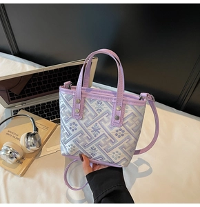 Close-up of lavender floral embroidered mini bucket bag with leather handles and strap