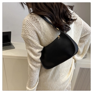 Minimalist black leather hobo bag with gold zipper shown on model in home setting