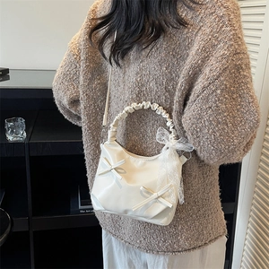 Chic white half-moon crossbody bag with decorative bows and pleated cloud handle