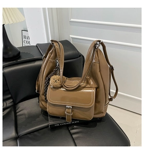 Detailed shot of brown glossy patent leather tote bag with pocket and plush bear charm