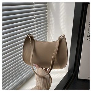 Detail of khaki leather baguette bag showing top zipper and stitching with stripe lighting