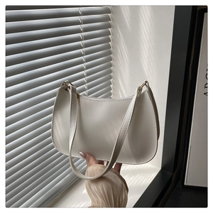 Minimalist white baguette bag with golden hardware shown in artistic natural light shadows