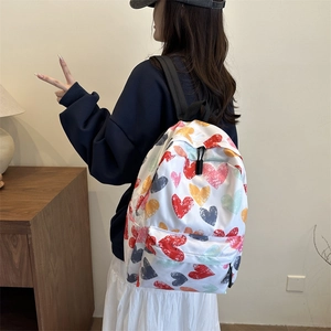 White casual backpack with colorful heart patterns and adjustable straps in home setting