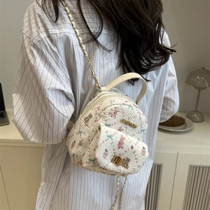 Mini cream backpack with floral bear pattern and gold chain strap shown on model