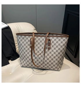 Close-up of taupe tote bag with letter print, leather trim, and sturdy shoulder straps