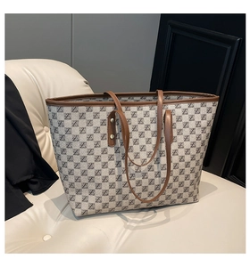 Detail der Monogramm-Canvas-Tasche mit braunen Ledergriffen und Metallnieten-Akzenten