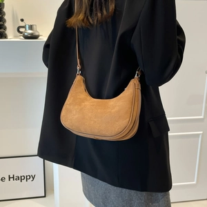 Brown suede hobo bag worn by model with minimalist silver hardware and sleek moon shape