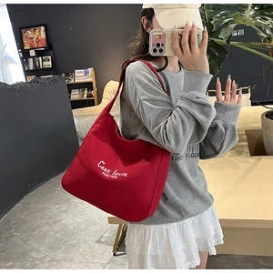 Detailed view of red canvas tote bag featuring white C'est la vie embroidery text