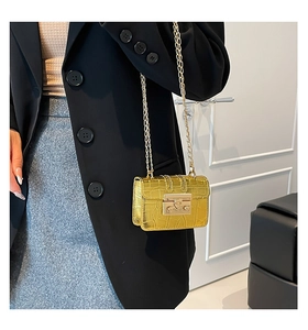 Detail of gold crocodile embossed crossbody bag with metallic chain and square lock