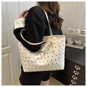 Close-up of white bubble texture tote bag featuring black bows and metal bow charm detail