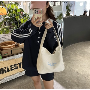 Detail of beige canvas shoulder bag featuring blue C'est la vie text print