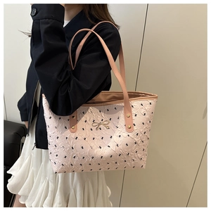Detail of light pink tote bag with floral print, textured finish and gold bow buckle