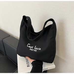 Detail of black canvas tote bag with C'est lavie print and wide integrated strap