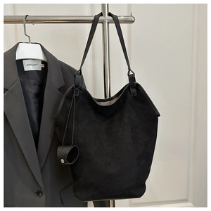 Vue détaillée du grand sac seau noir en daim mat avec cordons latéraux et fine bandoulière
