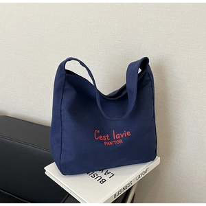 Detail of navy blue canvas tote bag with red embroidered C'est lavie lettering
