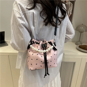 Sac seau rose à texture gaufrée avec motif papillon et poignée en perles élégante