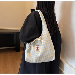 Dettaglio della borsa tote in tela a quadretti gialli e blu con etichetta e fiocco decorativo
