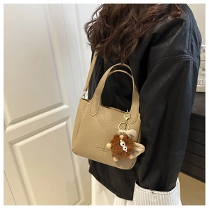 Sac seau en cuir abricot chic porté en bandoulière avec un pendentif peluche monstre