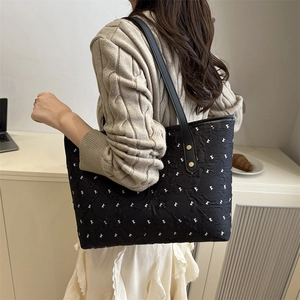 Quilted black tote bag with white bow patterns and dual straps for casual chic style
