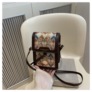 Detail of a brown leather crossbody bag with colorful diamond pattern and gold pendant