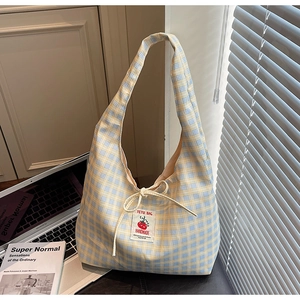 Dettaglio borsa tote in tela a quadri blu con fiocco a coulisse e toppa a pomodoro