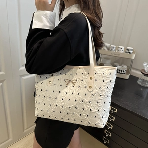 White large capacity tote bag with black bows and golden buckle worn by a model