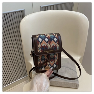 Close-up of geometric woven patterns and brown faux leather on a mini crossbody bag