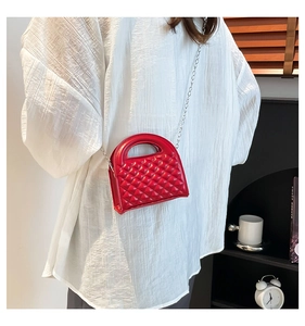 Macro detail of red quilted handbag with chain strap and glossy finish shown with model