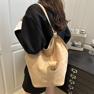 Brown suede tote bag with leather strap and triangle charm shown on a female model