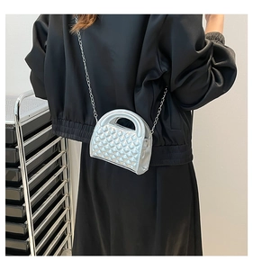Detail of silver quilted mini bag with metallic chain strap and top handle shown on model