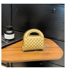Detail of light gold quilted crossbody bag with metal chain strap and arc handle
