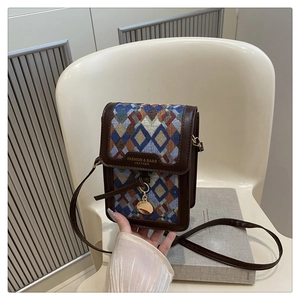 Detail of small woven crossbody bag with geometric pattern and brown leather trim