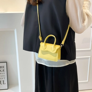 Mini sac à main jaune vif en cuir grainé avec bandoulière réglable porté par le mannequin