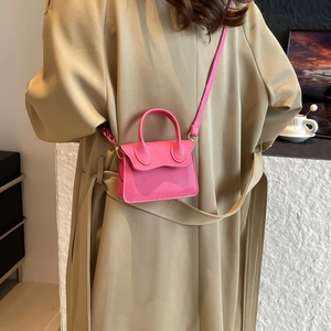 Petit sac bandoulière rose en cuir texturé porté par un mannequin en trench chic