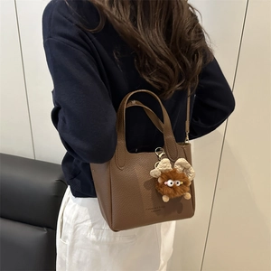 Sac seau marron à texture litchi avec breloque en peluche et inscription mode tendance