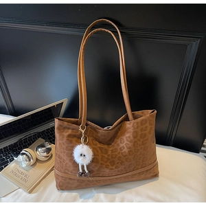 Dettaglio della borsa tote leopardata marrone con portachiavi di peluche e accessori