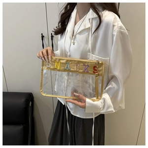 Detalle de bolso de mano de PVC transparente con bordado SNACKS de colores y borde dorado