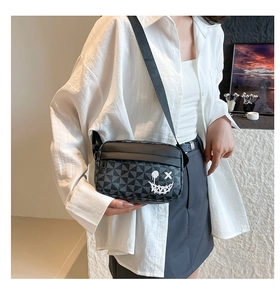 Detail view of crossbody bag featuring grey geometric patterns and a white graffiti smile