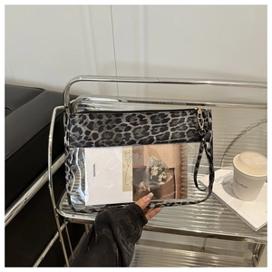 Detalle de bolso de PVC transparente con ribete de leopardo, asa de mano y cremallera