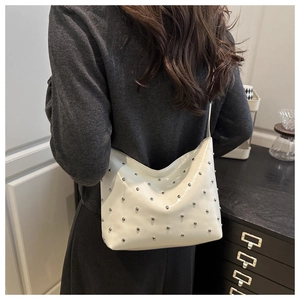 Detailed view of a white hobo bag with silver studs worn as an underarm shoulder bag