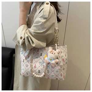 Détail du cabas blanc avec imprimé floral et bandoulière en chaîne de perles de luxe