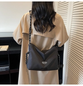 Close-up of black nylon crossbody bag with distinctive black and white rope shoulder strap