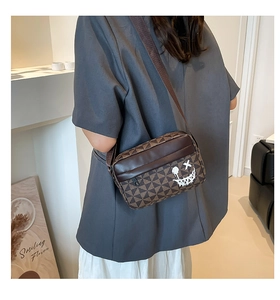 Detailed side view of a brown geometric print crossbody bag worn by a model