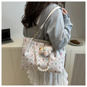 Detail der floralen Shopper-Tasche mit Perlenkette und süßem Lamm-Plüschanhänger