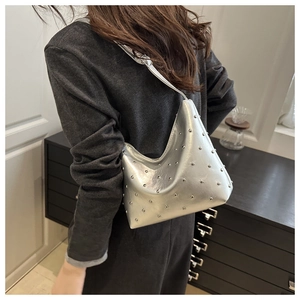 Detail of silver metallic hobo bag with round studs worn over a dark blazer