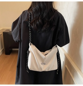 Detail of white nylon Hobo bag with woven rope strap on model in black coat