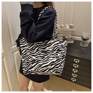 Detail einer Canvas-Tragetasche mit Zebramuster, Vordertasche und breiten Schultergurten