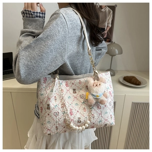 Detail of floral tote bag featuring a cute plush bear charm and pearl chain decoration