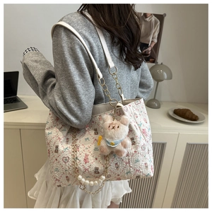 Detail of floral tote bag featuring 3D pleated texture, pearl chain, and a teddy bear charm